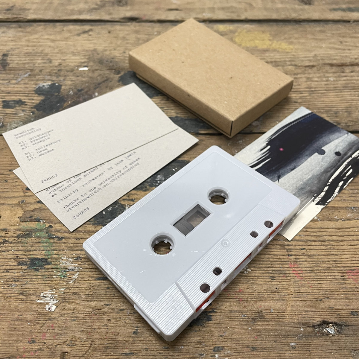 Photograph of a grey cassette, brown folded cover and printed text insert.