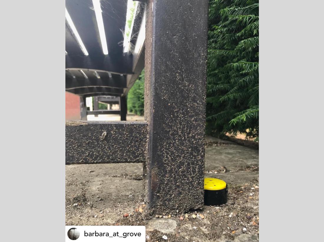 A photo of the yellow sound button placed at the bottom of a bench in a public park