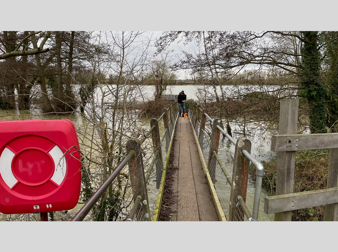Sound recordist Matt Shenton on a bridge in a flooded Stour Valley